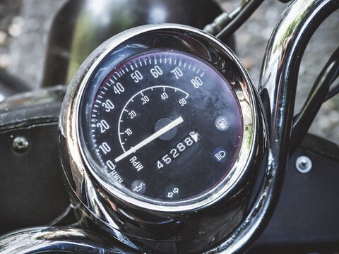 Black round speedometer with an arrow located on the handlebars of the motorcycle. Closeup photo