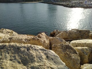 Yellow large stones and water.
Part of the sea. In the foreground yellow stones, the sun illuminates the water leaving a white path on the water.