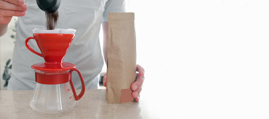 A man pours freshly ground coffee from a bag into a dripper for preparation v60. A professional set for making a pourover at home