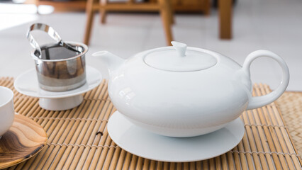 Teapot made of white porcelain. Beautiful professional teaware on a bambou tray.