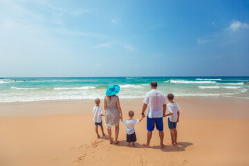 Happy young family in colorful clothes watching the sunset at the beach. Happy Family Lifestyle. Back view. Vacation. Phuket. Thailand