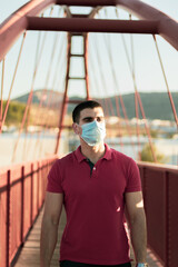 
young man posing on a bridge with mask