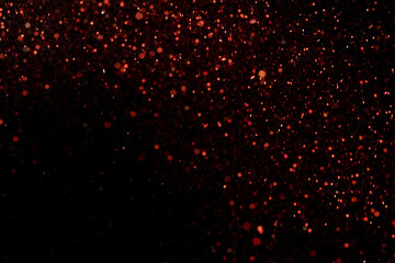 Beautiful, sparkling red glitter pouring down from above on a dark background