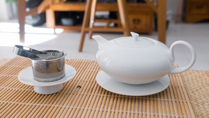 Teapot made of white porcelain. Beautiful professional teaware. Object precisely engineered to serve the best fresh tea. Metal tea filter on a porcelain support.