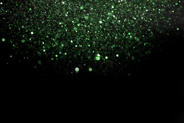 Beautiful, sparkling green glitter pouring down from above on a dark background