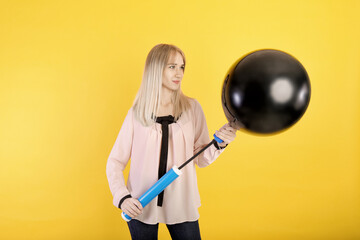 girl with a pump shakes a balloon. on a yellow background