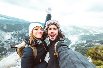 Happy couple taking a selfie hiking mountains - Successful hikers on the top of the peak smiling at...