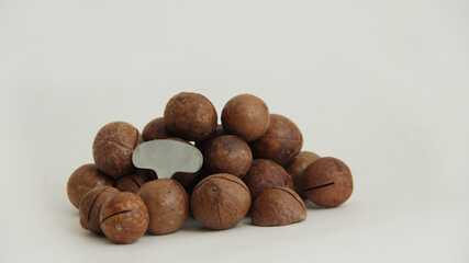 macadamia nuts whole and one split and a metal key on a white background