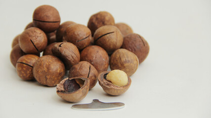 macadamia nuts whole and one split and a metal key on a white background