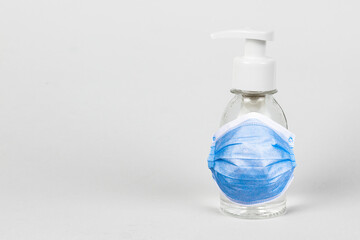 Sanitizer with antibacterial liquid and protective medical face mask. Pump bottle with antimicrobial transparent liquid gel on white background.