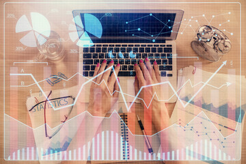 Double exposure of woman hands working on computer and forex graph hologram drawing. Top View....