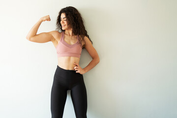 Fit young woman showing off her arm muscles and smiling