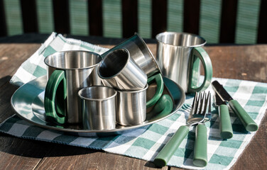 stainless steel camping and picnic utensils on a wooden table, utensils cutlery, dishes