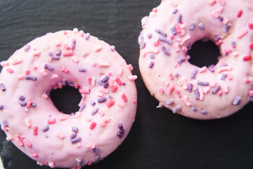 sweet glazed pink donuts close-up on a black tray.