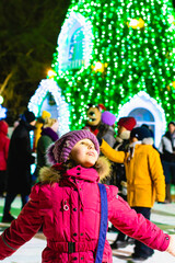 Kleines Mädchen vor einem großen Weihnachtsbaum im Park.