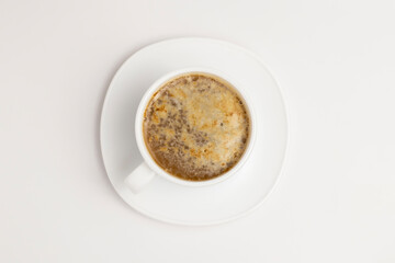 Beautiful foam of instant cappuccino in a white cup and saucer on a clean white background.