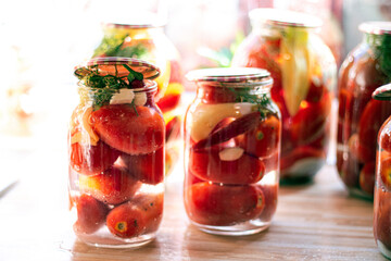 Fototapeta na wymiar Homemade pickled tomatoes in glass jars sealed with metal lid. Fermented tomatoes in transparent glass. Homemade canned tomatoes. Selective focus.