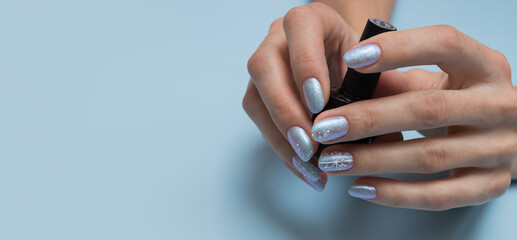 Female hands with winter manicure and a bottle of nail polish with copy space