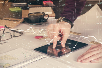 Double exposure of man's hands holding and using a digital device and forex graph drawing. Financial market concept.