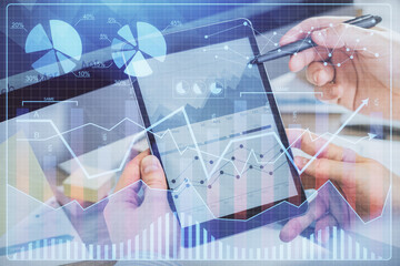 Double exposure of man's hands holding and using a phone and financial chart drawing. Market analysis concept.