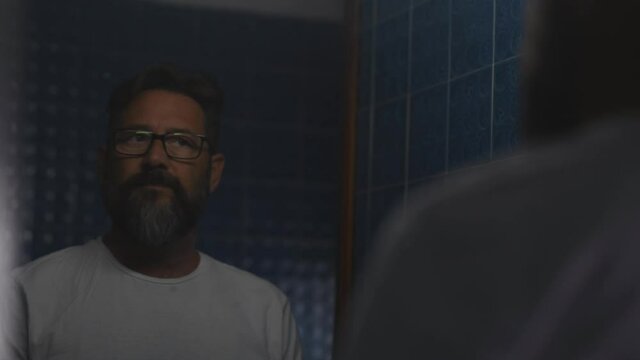 Sad and depressed man looking at himself in the mirror saying no with the head 