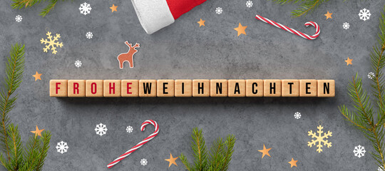 cubes with German message for MERRY CHRISTMAS and christmas decoration on concrete background