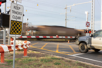 Coal train speeding through a level crossing.