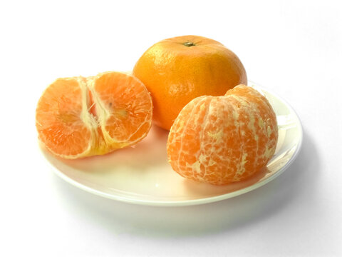 Closeup of juicy ripe orange tangerines (citrus reticula) peeled on a plate with a white background