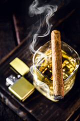cigar with smoke over whiskey glass, spot focus. Smoking concept, time to relax. View from the top
