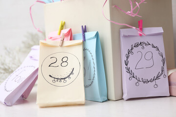 Colorful paper bags on white table, closeup. New Year advent calendar
