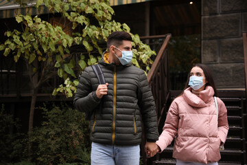 Couple in medical face masks walking outdoors. Personal protection during COVID-19 pandemic