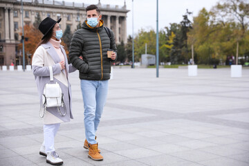 Couple in medical face masks walking outdoors. Personal protection during COVID-19 pandemic
