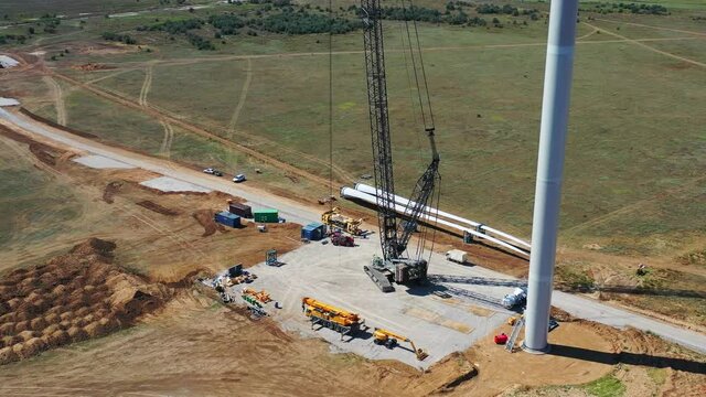 Drone footage of a wind turbine construction site, heavy machinery, big crane 4k