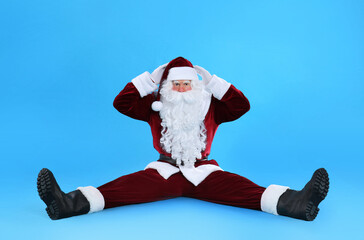 Funny Santa Claus sitting on light blue background