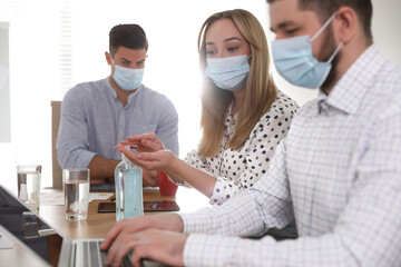 Group of coworkers with protective masks in office. Business meeting during COVID-19 pandemic