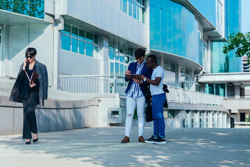 Obraz premium Two male colleagues reviewing their documents outside while their female colleague is talking on the phone.