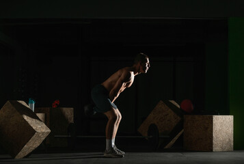 Fototapeta na wymiar High contrast side view photo of a healthy fitness guy doing workout using a kettlebell