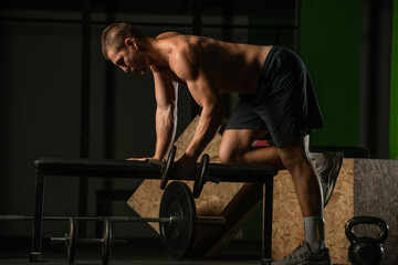 Fototapeta na wymiar Good looking young man doing triceps dumbbell kickback exercises with his left hand