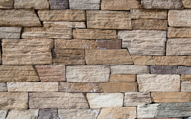 The texture of the wall is made of stone blocks of brick.Earthen colors of a brick wall of various shapes.Background, wallpaper, seamless.