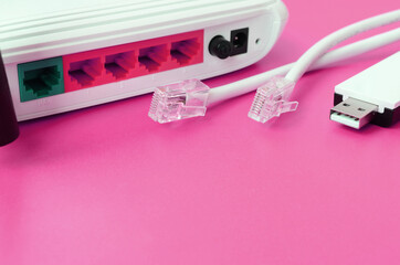 Internet router, portable USB wi-fi adapter and internet cable plugs lie on a bright pink...