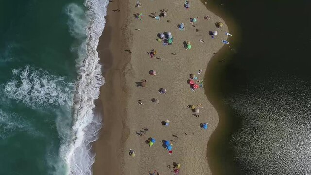 Top down view from Veleka Beach, Sinemorets,   filled with colorful umbrellas during the Festival of kites. Strong waves splashing over the beach.