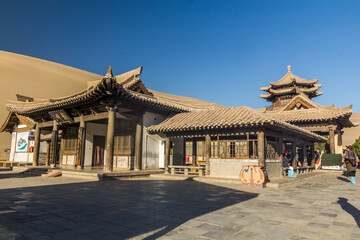 Fototapeta premium DUNHUANG, CHINA - AUGUST 21, 2018: Pavilion at Crescent Moon Lake at Singing Sands Dune near Dunhuang, Gansu Province, China