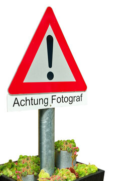 Warning sign in a large flowerpot with text: Attention photographer -Achtung Fotograf