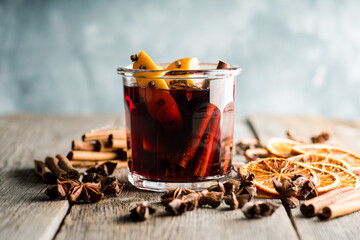 Mulled red wine with oranges and different spices in glass on the rustic background. Christmas food. Winter decorations. Selective focus. Shallow depth of field.