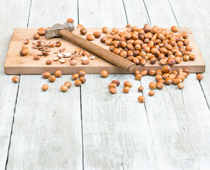 Nuts. Hazelnuts and hammer on shabby wooden table