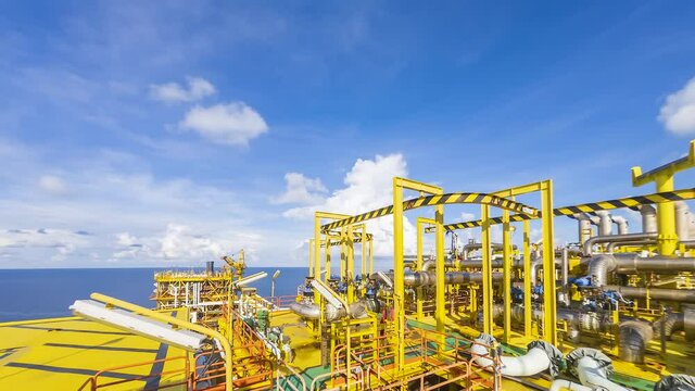 Oil and gas industry at offshore. 4K time lapse scene at oil and gas platform complex with dramatic clouds movement and blue sky. 