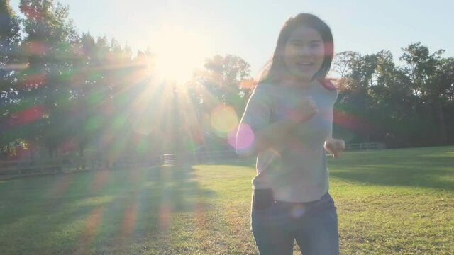 relax casual freedom asian female mature adult smiling and run with happiness and cheerful in public garden forest park with falre sunlignt