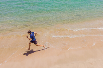 Runner running on beach by the ocean - view from above. Man athlete training cardio jogging doing...
