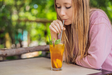 Eco friendly woman using reusable stainless steel straw to drink fruit tea