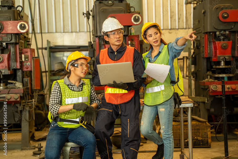 Poster Industrial engineer with factory worker while using Laptop working in a factory.